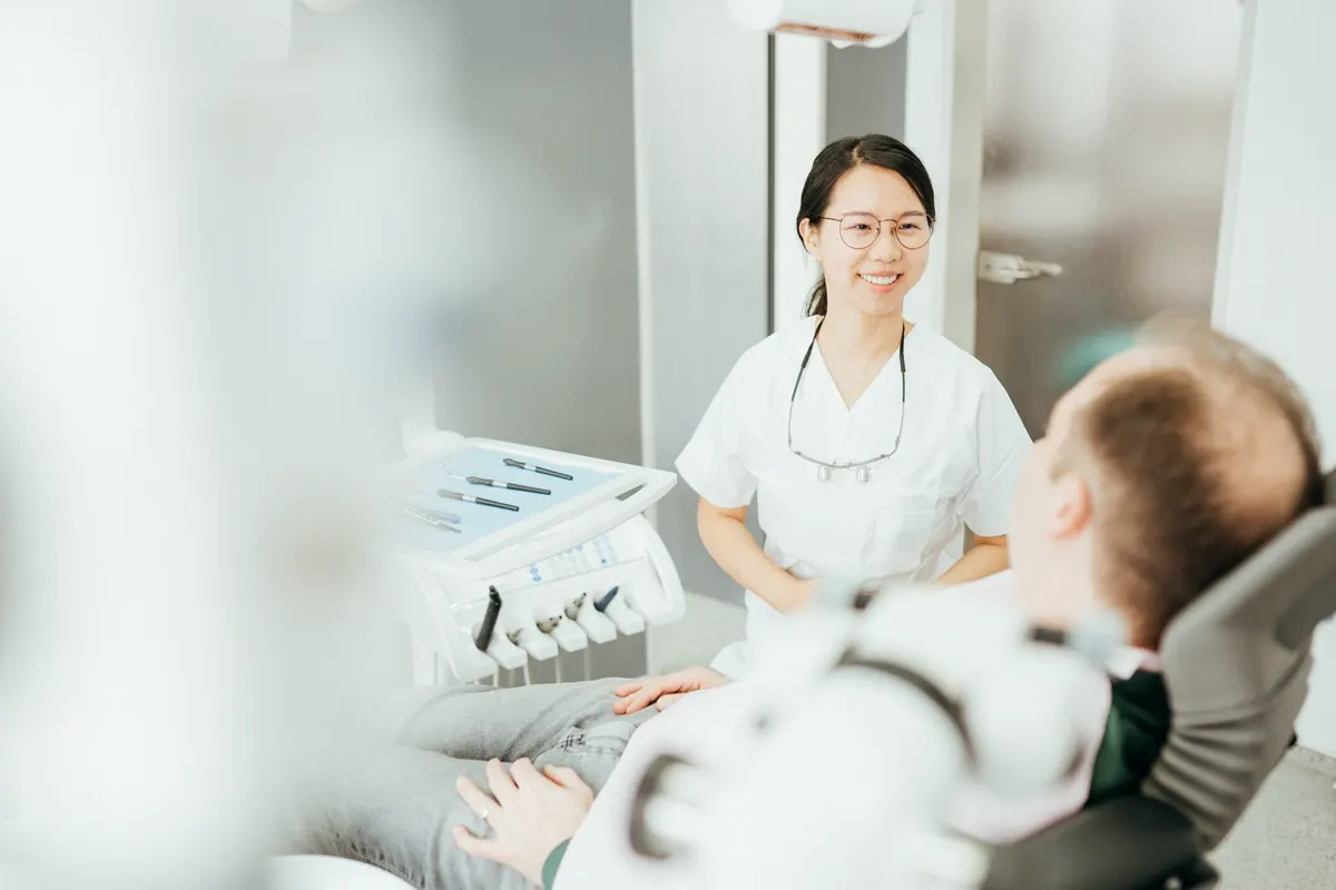 Dr. Jiang im Gespräch mit einem Patienten im Behandlungsstuhl